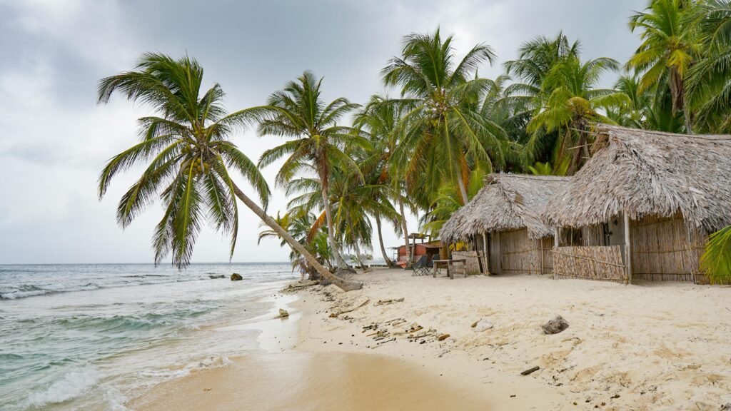 Idyllic beach scene with palm trees and huts in Guna Yala, Panama, showcasing tropical island paradise.